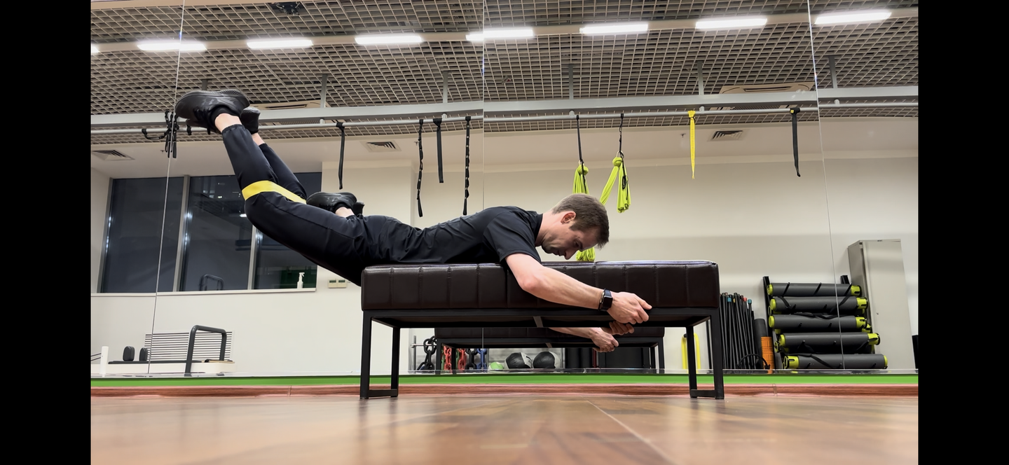 Обратная гиперэкстензия на скамье с мини-бэндом между ногами