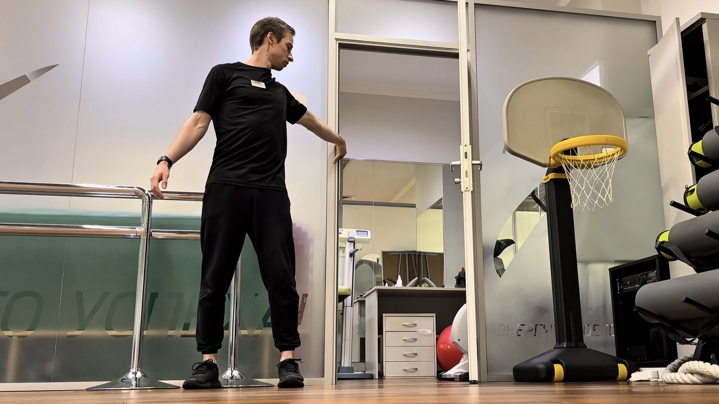 Растягивание бицепса руки держась за дверную коробку