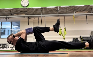 Сгибания ног с кирпичиком для йоги зажатым между локтями и коленями (вариация мертвого жука)